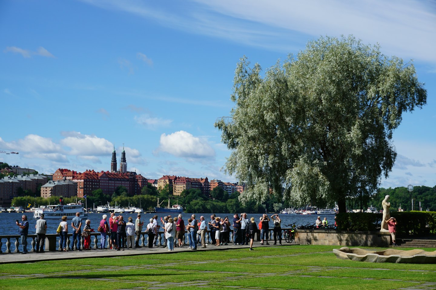 Ludzie stojący przy kamiennym murze z widokiem na panoramę miasta.